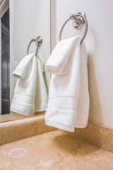 Close up of a white towel hanging on a metal ring mounted on the bathroom wall