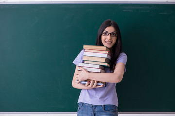 Young female teacher student in front of green board