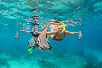 Happy family - mother, kid in snorkeling mask dive underwater, explore tropical fishes Platax ( Batfish). Travel lifestyle, beach adventure, swimming activity on summer with child. Focus on fishes - obrazy, fototapety, plakaty