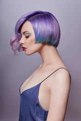 Portrait of a woman with bright colored flying hair, all shades of purple. Hair coloring, beautiful lips and makeup. Hair fluttering in the wind. Sexy girl with short  hair. Professional coloring