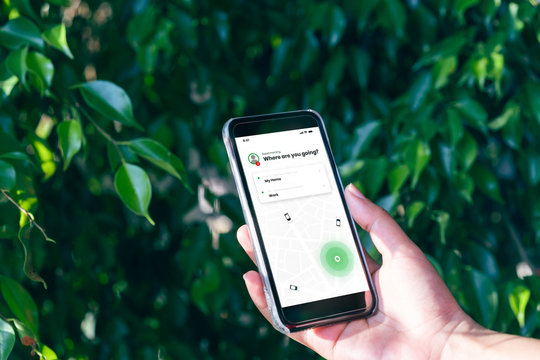Hand holding mobile phone device outdoors to book taxi using ride hailing app - Woman booking internet taxi service using smartphone device for journey to work - cab, commuting and lifestyle concept