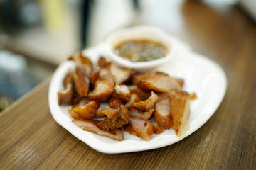 Charcoal-boiled pork neck (grilled pork) served with spicy dipping sauce (Jaew), Thai food recipe, Selective focus.