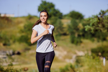 Girl runner runs along in nature in summer.