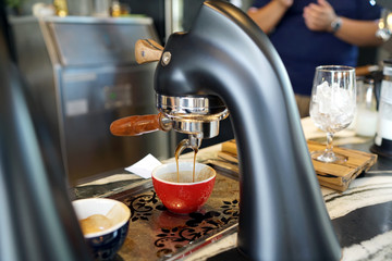 Under counter espresso system in the bar, Coffee machine pours espresso to glass shot then barista...