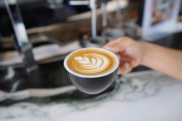 Hot Latte - A cup of coffee with milk and beautiful leaf pattern latte art on marble table and blurred background, Perfect for breakfast time.