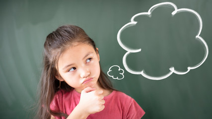  little girl standing against chalkboard with thinking bubble