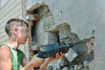 A man with a jackhammer makes an opening in the wall.