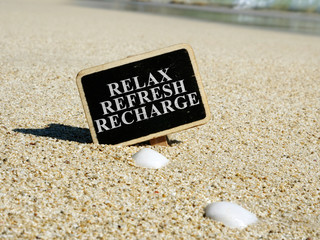Relax refresh recharge sign on a beach.