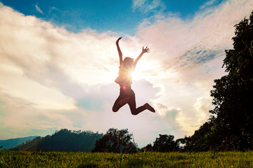 Silhouette of happy child jumping playing on mountain meadow at sunset time