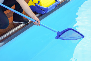 Pool cleaner during his work. Cleaning robot for cleaning the botton of swimming pools. Hotel staff worker cleaning the pool.  