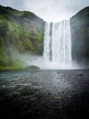 Skogafoss waterfall in green mountain landscape in Iceland