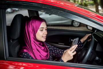 Muslim Female with her smartphone in her car. Car insurance concept.