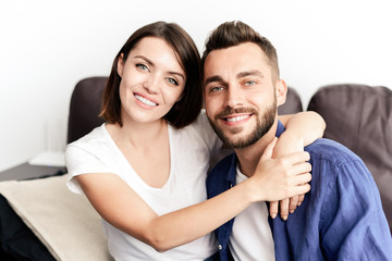 Portrait of cheerful young beautiful couple sitting on sofa