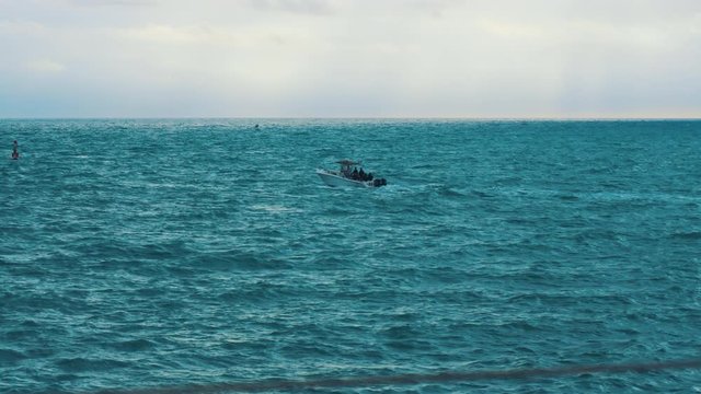 Center console boat in open sea waters crashing through waves, long shot