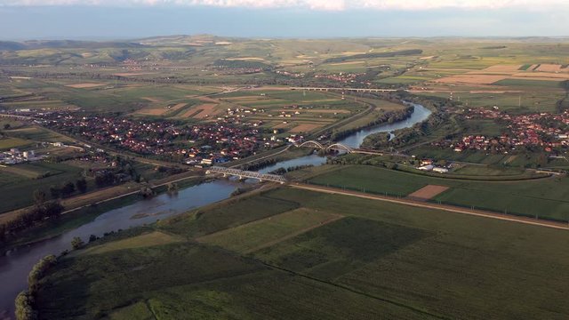 Aerial view of Mures river crossing small town and passing through green fields