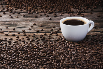 White cup of coffee with beans on brown wooden table