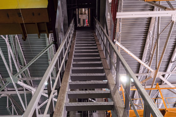 Fototapeta na wymiar Steel ladder in engineering plant shop. Landing staircase on overhead crane.