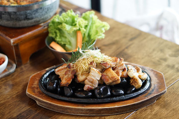Grilled pork belly served on hot stones, Topped with chopped spring onions and rosemary leaf, Korean BBQ style, The national street food of Korea.