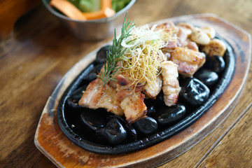 Grilled pork belly served on hot stones, Topped with chopped spring onions and rosemary leaf, Korean BBQ style, The national street food of Korea.
