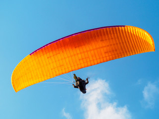 Paraglider is flying in the blue sky.