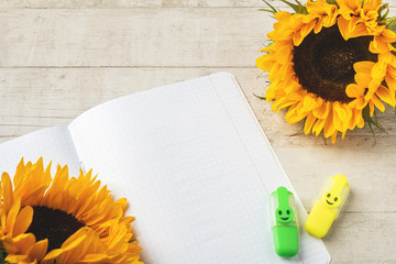 Sunflowers, copybook and markers on a white wooden background. Back to school concept. Copy space.
