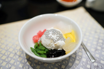 Homemade coconut ice cream topped with jackfruit, Thai pandan short vermicelli (lod chong), black grass jelly, attap fruit and water chestnut (tab tim krob), Thai Traditional Dessert.