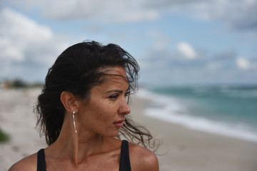 portrait close-up of brown-eyed brunette against the sea