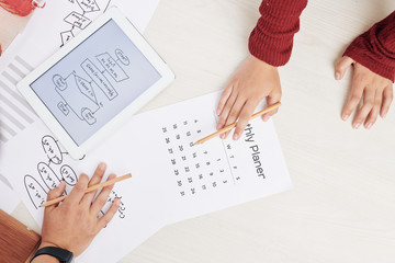 Hands of young programmers setting project deadline and drawing block scheme for new project