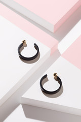 Detail close-up shot of a pair of congo earrings with golden fasteners. The hoop earrings are made...