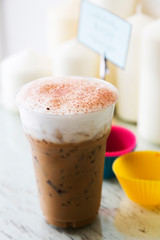 Ice coffee with milk foam on table