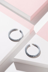 Detail close-up shot of a pair of patchy congo earrings with steely fasteners. The hoop earrings...