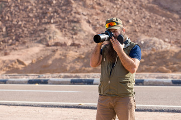 Obraz premium A bearded man on the mountain of Moses with a camera, pilgrimage to the holy places. Nature photographer taking photos in the mountains.
