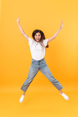 Fototapeta na wymiar Full length image of happy brunette woman with long hair smiling while rejoicing and dancing
