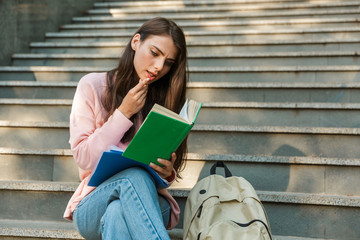 Attractive young smiling girl student reading a book