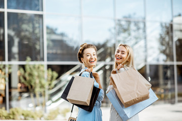 Portrait of a two happy women with shopping bags standing in front of the shopping mall