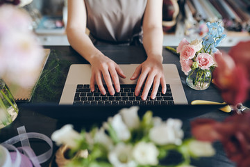 Close-up of unrecognizable female florist standing at desk