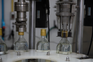 Bottles machines working in manufacture, filling fresh water to glass bottles