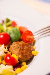 Colorful fresh vegetable salad with meatballs and corn seeds