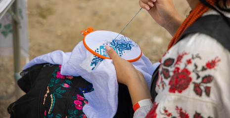embroidery process of blue patterns tracery on white cloth by tender woman hands, life style and...