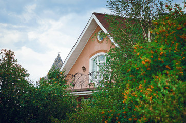 Fragment of a modern country house surrounded by green trees.