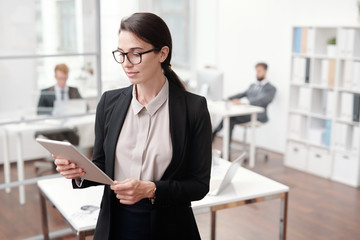 Waist up portrait of female business manager using digital tablet