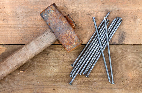 Vintage old rusty hammer and nails lying on wooden boards. Top view