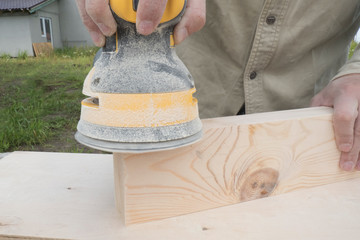 Close-up of a carpenter working with an orbital sander. Concept of construction, woodwork, carpentry