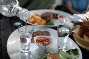 Person pouring vodka into glasses