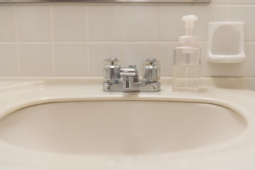 Fototapeta na wymiar Washbasin and hand soap in the white bathroom of the hotel