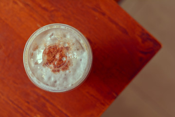 Top view Ice coffee (cappuccino, latte, mocha) with cocoa powder topping in plastic cup on blurry wooden table in cafe and restaurant with copy space for your text. Vintage tone.