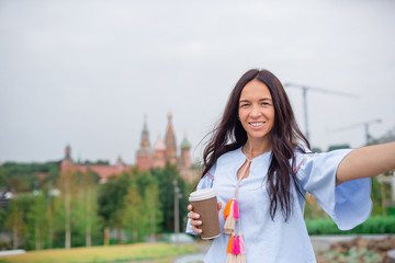 Naklejka premium Happy young urban woman drinking coffee in european city.