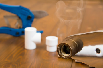 close-up of a heated soldering iron with smoke from a melted plastic pipe, on a wooden background