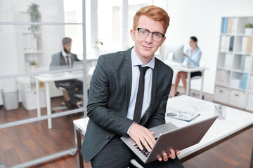 Fototapeta na wymiar Smiling Red Haired Businessman Holding Laptop
