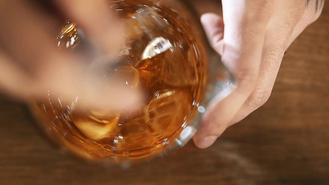 Extra close-up glass. Bartender mixes an alcoholic cocktail in a glass with ice